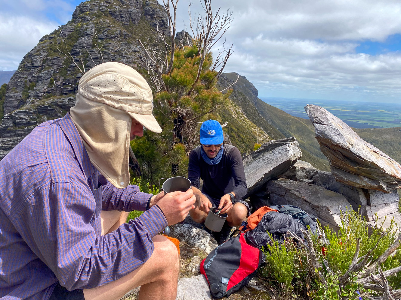 Kenny and Johno at the top of a mountain preparing some food or drinks